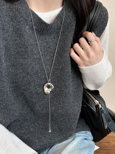 Detail of silver long sweater necklace featuring an irregular minimalist hollow pendant