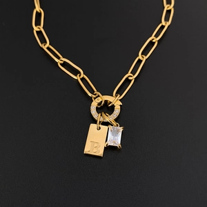 Close-up of gold paperclip chain necklace with letter B tag and rectangle CZ pendant