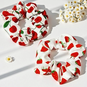 Détail de chouchous doux avec imprimés fraises et cerises sur un tissu texturé