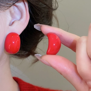 Macro detail of red teardrop earrings showing side profile and smooth lacquer finish