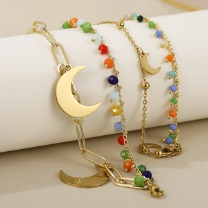 Detail of gold double-layer chain bracelet featuring moon charm and colorful beads