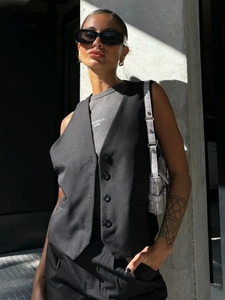 Detail of black V-neck waistcoat featuring single-breasted buttons and structured fabric