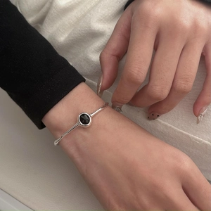 Close-up of minimalist S925 silver wave bangle with an oval black onyx gemstone