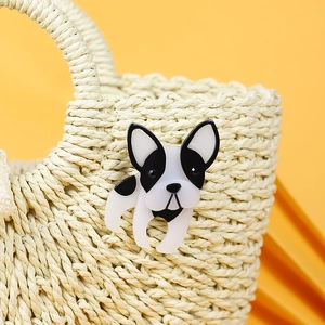Handmade black and white acrylic French Bulldog brooch pinned on a beige woven bag