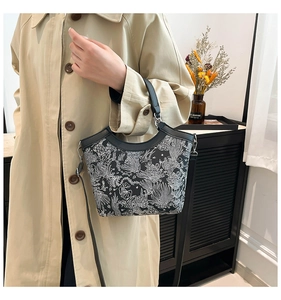 Detail of vintage floral canvas tote bag with leather straps on a beige trench coat