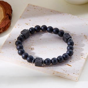 Detail of matte black beads and square lava stones with metal spacers on stone surface