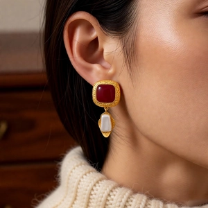 Detail of vintage square resin earring with white pearl drop on model wearing knit sweater