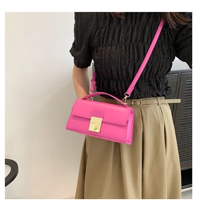 Detail shot of the magenta crossbody bag with golden metal buckle and leather texture