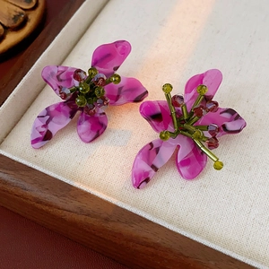 Macro detail of vintage floral resin earrings with purple petals and beaded core