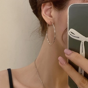 Polished silver geometric hoop earrings worn by a model in a minimalist fashion style