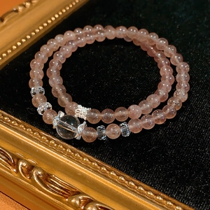 Macro shot of double-strand strawberry quartz bracelet with crystal beads on black velvet