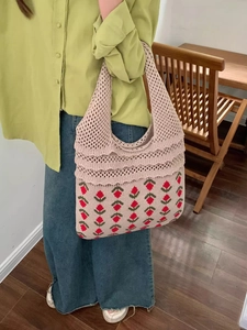 Close-up of pink knitted tote bag featuring red strawberry patterns and woven handles
