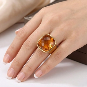 Detail view of a large cushion-cut amber gemstone set in a wide gold stainless steel band