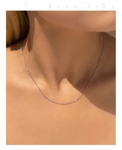 Macro detail of minimalist S925 sterling silver water wave chain on female neck