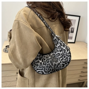 Detailed view of trendy leopard print crescent bag with silver hardware on camel coat