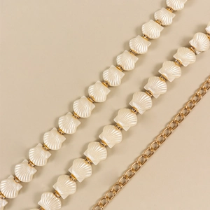 Close-up of golden metal chain with shell-shaped pearl beads and sparkling rhinestones