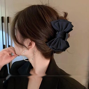 Detail of large black satin bow claw clip worn by model for elegant hairstyle look