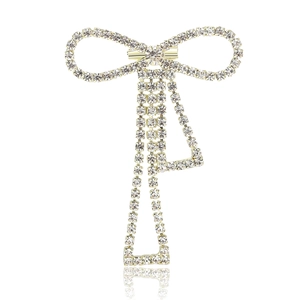 Elegant gold bow brooch with sparkling rhinestones and long tassels on white background