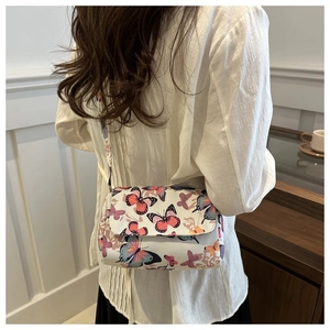 Chic white crossbody bag with butterfly print shown on shoulder for summer style