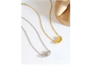Detailed view of silver and gold bean-shaped pendants on fine chain necklaces