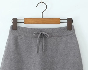 Close-up of gray knit skirt featuring elastic waistband and drawstring detail on hanger