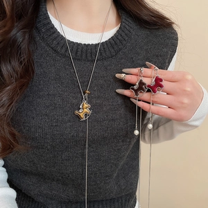 Détail de trois pendentifs cheval à bascule colorés avec perles sur un collier long