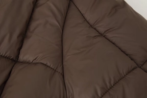 Gros plan sur la texture du tissu matelassé marron foncé avec rembourrage et coutures