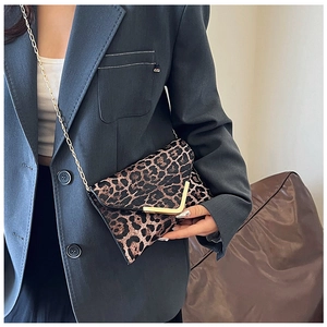 Detail of leopard print bag featuring a gold V-shaped buckle and fine chain strap