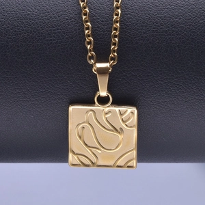 Macro view of golden square pendant with floral engraving on stainless steel chain