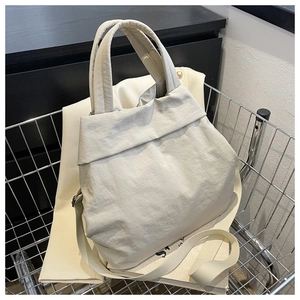 Detail of cream pleated nylon tote bag in shopping cart with shoulder strap view