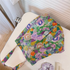 Detail of floral canvas tote bag with vibrant oil painting patterns on a white chair