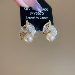 Detailed view of gold leaf earrings with crystals and dangling pink pearls