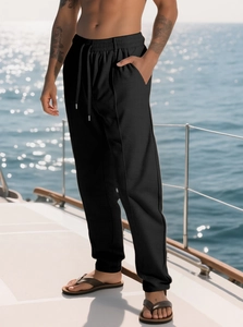 Dettaglio dei pantaloni neri con coulisse da uomo sul ponte di uno yacht con vista mare