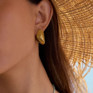 Boucles d'oreilles coquillage en or 18K avec texture nervurée dans un décor de plage