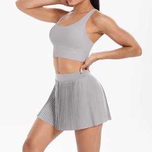 Detail of grey pleated tennis skirt and racerback sports bra on a model for fitness