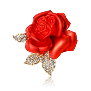 Elegant red rose brooch with gold leaves and shimmering rhinestones on white background