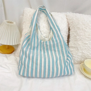 Large striped canvas shoulder bag displayed in a cozy home setting with warm lighting