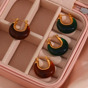 Detail of green and brown resin hoop earrings with gold clasps in a pink velvet jewelry box