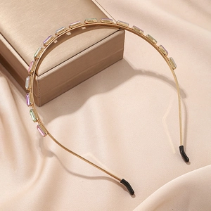 Detail of gold headband with colorful rectangular crystals on beige silk fabric