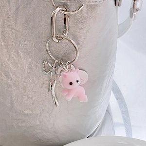 Portachiavi con gatto rosa e fiocco d'argento su una borsa metallica testurizzata