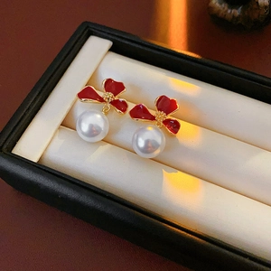Detail of red flower pearl earrings with gold finish on a jewelry box background
