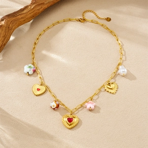 Detail of gold-plated chain necklace with ceramic heart and floral charms on wood