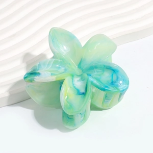 Detail of flower hair claw clip with green and blue marble texture on white background