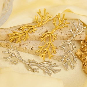Detailed view of branch-shaped gold and silver stainless steel earrings on a stone base