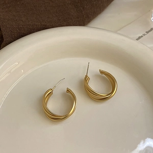 Detail view of gold matte triple C-shaped hoop earrings on a ceramic dish