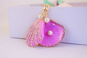 Close-up of pink shell keychain with rhinestones, pearl accents, and gold lobster clasp