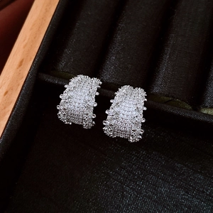 Close-up of silver pave-set zircon hoop earrings on black velvet jewelry tray display