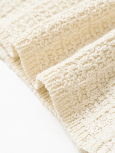 Macro shot of cream knit texture and ribbed edge detailing on summer short sleeve top