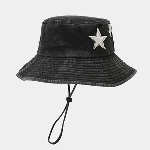 Detail of black washed denim bucket hat featuring white star patch and adjustable chin strap