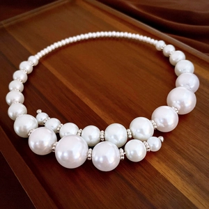 Macro view of oversized faux pearls on a choker with metallic spacer beads on wood